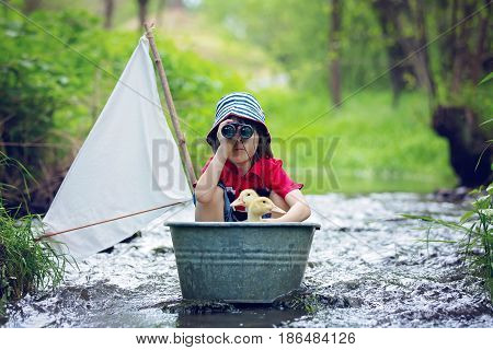 Cute Child, Boy, Playing With Boat And Ducks On A Little Rive