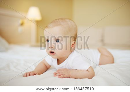 Portrait of a young child in white clothes against the background of a baby crib