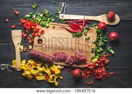 slicing sausage on cutting Board with ingredients pepper tomato