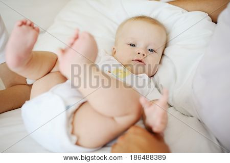 Portrait of a young child in white clothes against the background of a baby crib