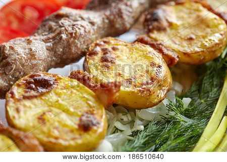 Grilled barbecue Lula Kebab with minced meat potatoes fresh vegetables and greens