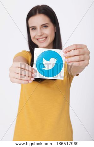 KIEV, UKRAINE - AUGUST 22, 2016: Woman hands holding Twitter logotype icoi bird printed paper close up. Twitter is an online social networking service that enables users to send and read short messages.