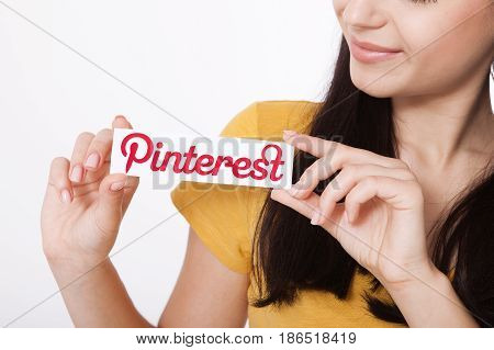 KIEV, UKRAINE - AUGUST 22, 2016: Woman hands holding Pinterest ilogotype icon printed paper close up. Is photo sharing website.