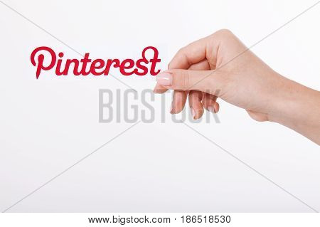 KIEV, UKRAINE - AUGUST 22, 2016: Woman hands holding Pinterest ilogotype icon printed paper close up. Is photo sharing website.