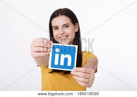 KIEV, UKRAINE - August 22, 2016: Woman hands holding Linkedin icon sign printed on paper on white background. Linkedin is a business social networking service.
