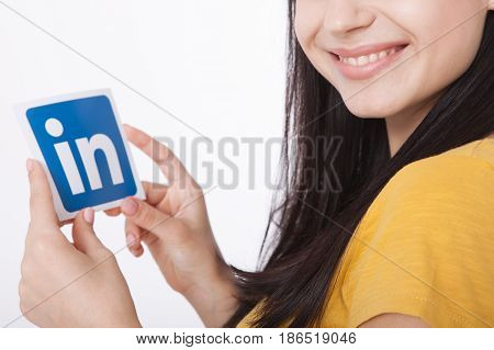 KIEV, UKRAINE - August 22, 2016: Woman hands holding Linkedin icon sign printed on paper on white background. Linkedin is a business social networking service.
