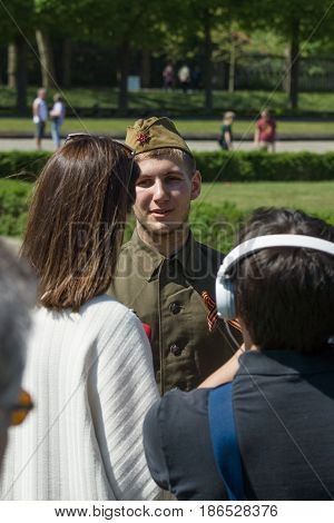 BERLIN - MAY 08 2016: Victory in Europe Day. Soviet War Memorial in Treptower Park. Journalist Ukrainian TV station 1+1 is interviewing a young man dressed in the form of a Soviet soldier during the war.
