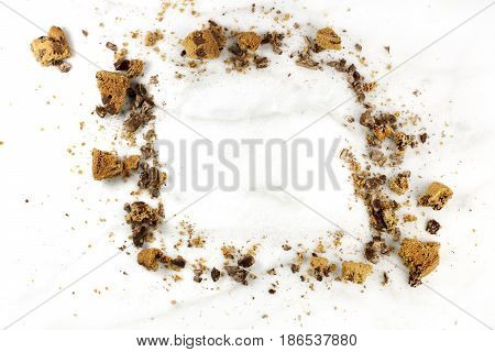 A frame made up by chocolate chips cookie crumbs, shot from above on a white marble background, with a place for text