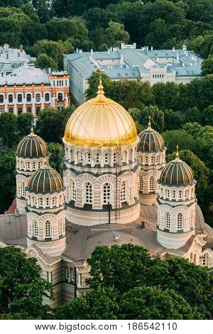 Riga, Latvia. Riga Cityscape. Top View Of Riga Nativity Of Christ Cathedral - Famous Church And Landmark In Summer Evening. Golden Yellow Domes.