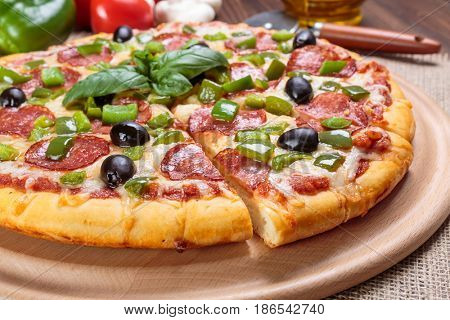 Sliced Pepperoni Pizza with Black Olives and Green Pepper on a cutting board