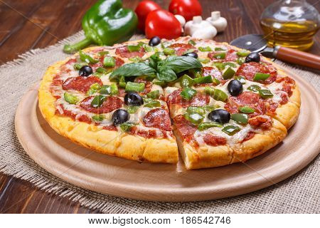 Sliced Pepperoni Pizza with Black Olives and Green Pepper on a cutting board