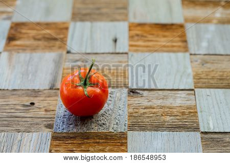 Wooden table from different wood mosaik textures, as chess board and fresh organic ripe tomato with water drops. Healthy eating concept, antioxidant and diet