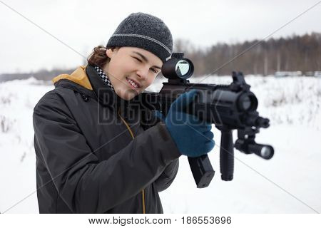 Happy teenager with gun takes aim during lasertag game outdoor at winter