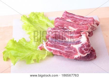 Raw beef edges and lettuce leaf on wooden desk isolated on white background from above and copy space. ready for cookin