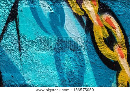 Close up of blue, white, orange, yellow and black graffiti with chain links on a brick wall