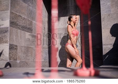 Attractive sexy woman under the shower outdoors near swimming pool at luxury hotel resort.