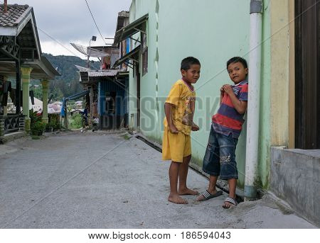 BERASTAGI INDONESIA 15 MAY 2017 : Two indonesian children near the wall on the street at countryside area of Berastagi city Northern Sumatra.
