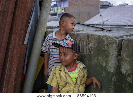 BERASTAGI INDONESIA 15 MAY 2017 : Two indonesian boys near the wall on the street at countryside area of Berastagi city Northern Sumatra.