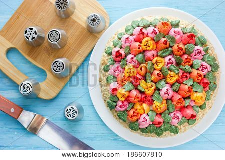 Delicious cake decorated with colorful cream flowers tulips top view