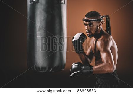 Determined Young Muay Thai Fighter In Boxing Gloves Training Thai Boxing With Punching Bag, Boxing G