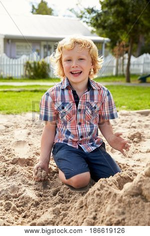 Male Pupil At Montessori School Playing In Sand Pit At Breaktime