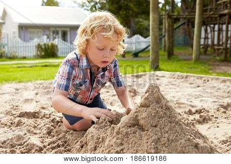 Male Pupil At Montessori School Playing In Sand Pit At Breaktime