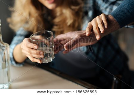 Everything is okay. Strong male hand stretching to take glass and drunk female touching it