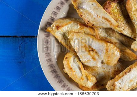 Flat lay above fried chicken breasts on the plate above blue wooden planks board.