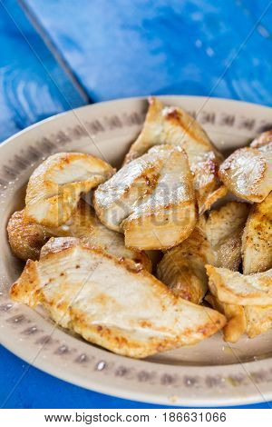 Flat lay above fried chicken breasts on the plate above blue wooden planks board.