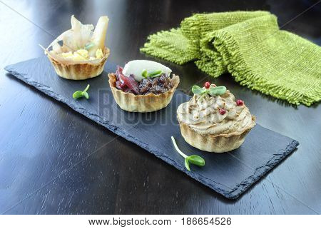 Three tartlets with fillings on a dark background