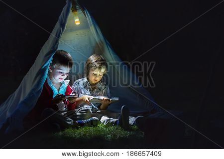 Cute Little Brothers, Playing On Tablet And Telephone At Night In Campside