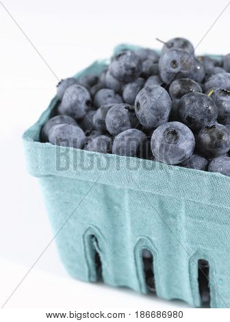 A green carton filled with a bunch of Blueberries