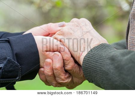 Close up picture of a young woman's hands holding an elderly female's hands