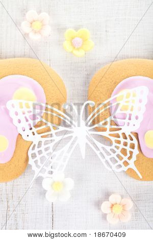 ornate paper batterfly and ginger cookies with sugar flowers on white table, shallow dof