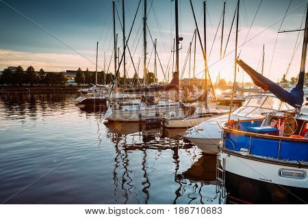 Riga, Latvia - July 1, 2016: Riga, Latvia. Many Yachts Moored At The City Pier Harbour Bay And Quay In Summer Sunny Evening. Reflections From Boats In Water Of Western Dvina River.