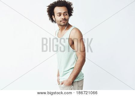 Young african man in headphones standing in profile looking in side. White background. Copy space.