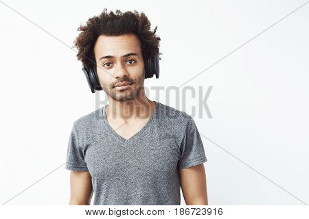 Portrait of handsome african man in headphones listening to music over white background. Copy space.