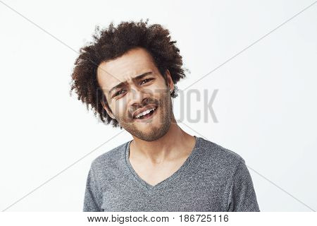 Upset displeased african man looking at camera over white background. Copy space.