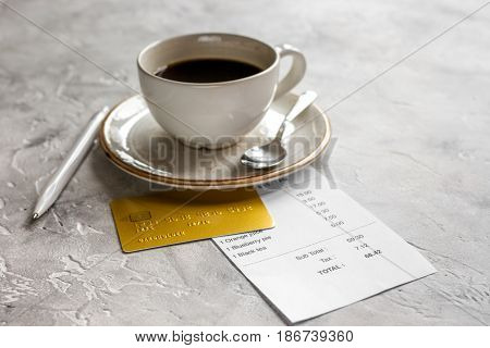 cup of coffee and receipt bill for payment by credit card on stone table background