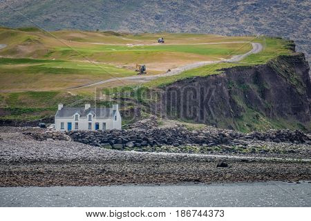 House on the rocky coast as seen from the Ballingskelligs Bay Beach in Waterville, County Kerry, Ireland