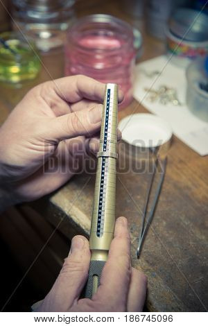 Process of wedding ring crafting. Close up of jeweler  using ring mandrel to measure the size of wedding ring