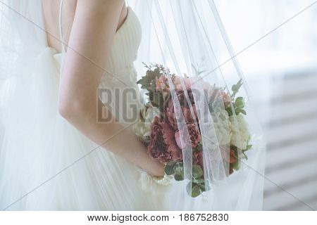 Beautiful bride is holding a wedding colorful bouquet. Beauty of colored flowers. Close up bunch of florets. Bridal accessories. Female decoration for girl. Details for marriage and for married couple