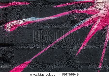 Close up of blue, white, pink, red and black sunburst painted on a brick wall