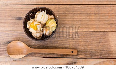 top view of cape gooseberry (Physalis) in wooden bowls and wooden spoon
