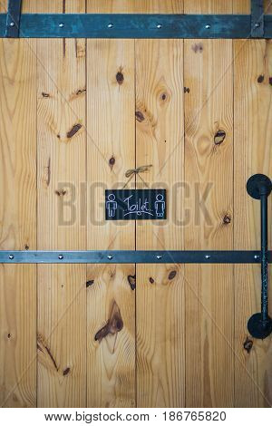 wooden big toiler door men and women vintage old style with black iron handle and toilet sign / wooden toilet door