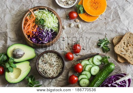 Healthy vegetarian food set background with free space for text. Cabbage avocado tomatoes cucumbers pumpkin wild rice on a paper background top view. Flat lay
