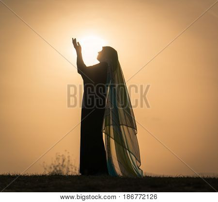 Woman with her hands up on sunset