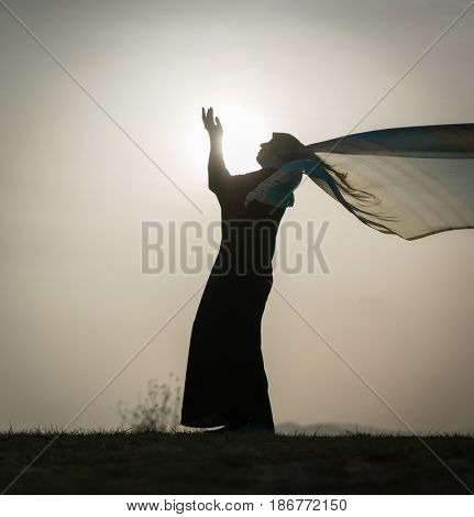 Woman with her hands up on sunset