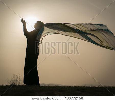 Woman with her hands up on sunset