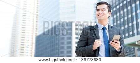 Young businessman using mobile phone while walking in the city - business travel and mobile roaming concepts panoramic banner